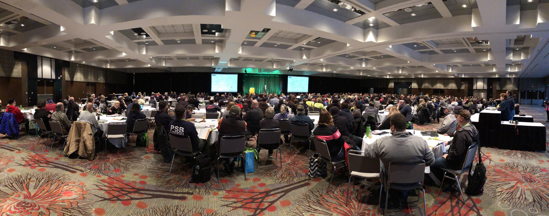 People at the conference sitting at tables listening to speakers.